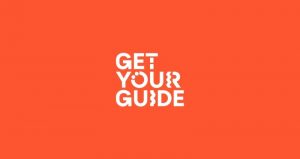 Logo GetYourGuide màu trắng trên nền đỏ cam, một trong những nền tảng thuộc Top OTA Tour Ở Việt Nam cung cấp dịch vụ đặt tour đến Đồi cừu Suối Nghệ.